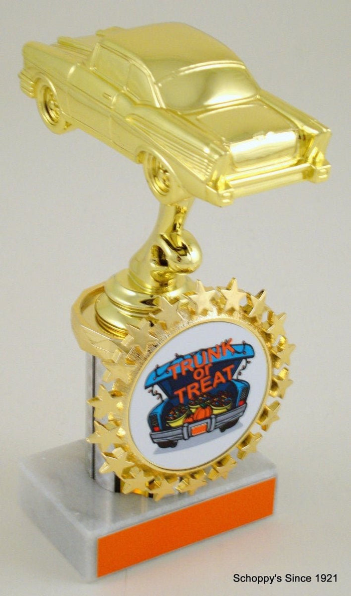A novelty trophy shaped like a gold classic car on a pole, with a circular 'Truck or Treat' badge on the base and a gray and orange pedestal. The photo is taken against a light gray background.