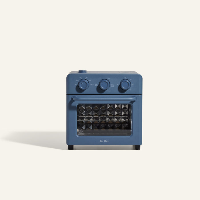 The Wonder Oven is a compact, blue countertop air fryer oven with three control knobs and a glass front door. Versatile as both an air fryer and toaster oven, it’s shown against a plain light background.